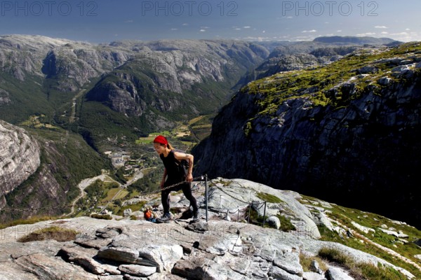 Hikers climbing Mount Kjerag with breathtaking mountain scenery in the background, Lysefjord, Norway