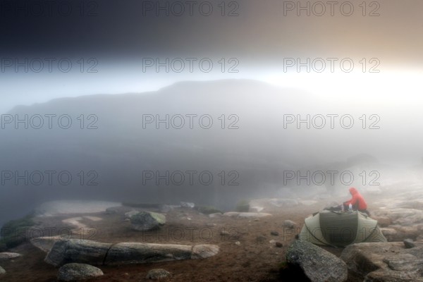 Tent at sunrise in thick fog with glowing horizon on a plateau, Lysefjord, Rogaland, Norway