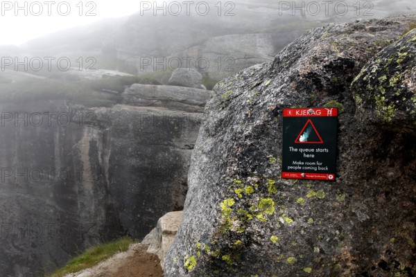 Warning on rock against the backdrop of the misty Kjerag landscape, Lysefjord, Rogaland, Norway