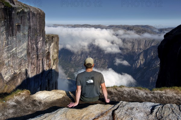 Tourist enjoying spectacular views of fog-shrouded Lysefjord, Lysefjord, Rogaland, Norway