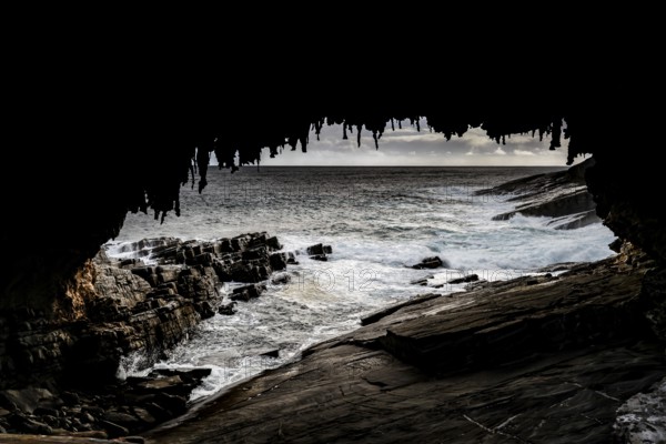View of the ocean and rugged coastline through the dark cave of Admiral's Arch, Kangaroo Island, South Australia, Australia