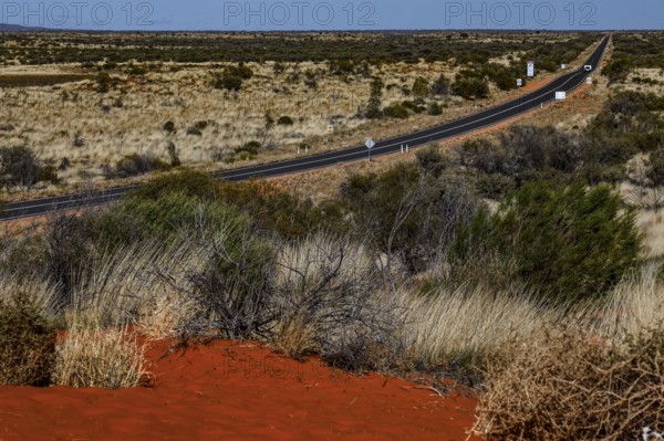 Long desert road through the Australian outback with red sand and vegetation, zero