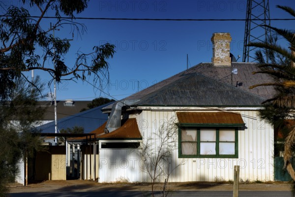 Single-family house in Marree with surrounding vegetation and blue sky, Marree, South Australia, Australia