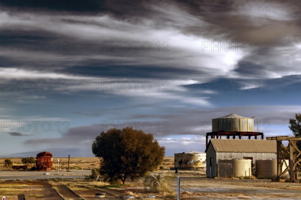 Industrial building with water tower in rural Marree under dramatic sky, Marree, South Australia, Australia