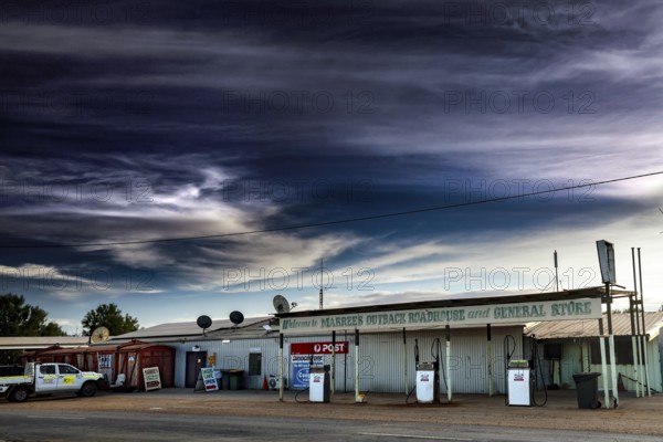 Abandoned gas station and storefront in Marree under dramatic sky, Marree, South Australia, Australia