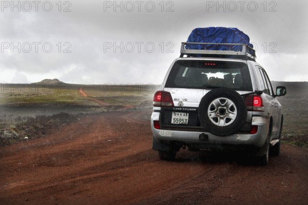 A Landcruiser drives along a track on the Sanetti Plateau under overcast skies, Bale Mountains, Sanetti Plateau, Ethiopia