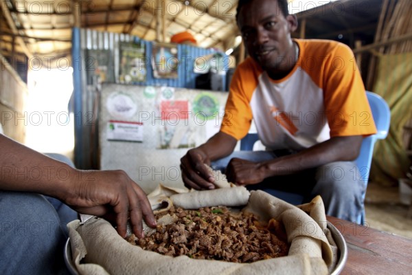 Men in restaurant in Berhaile enjoying traditional Tibs food, Berhaile, Ethiopia