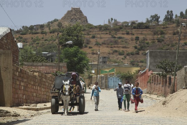 Locals walk down a dusty road surrounded by hills, Axum, Tigray, Ethiopia