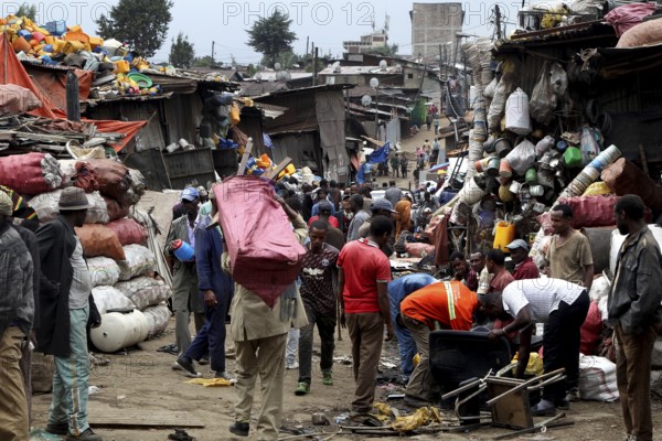 People carry large bags on their shoulders through the bustling Mercato in Addis Ababa, Addis Ababa, Ethiopia