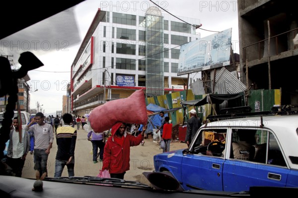 Busy street scene with passers-by and cars in front of modern buildings, Addis Ababa, Mercato, Ethiopia