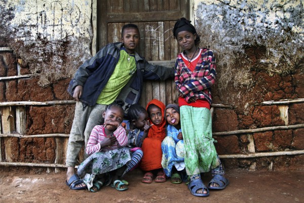 Children in colorful clothes pose happily in front of a traditional house, Dorze village, Ethiopia