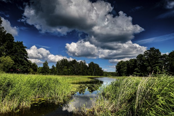 Lush landscape with river and impressive cloud formations in Ginuciai