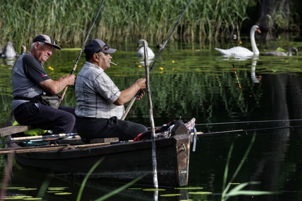 Two men fishing in a boat on a calm lake surrounded by nature, Ignalina, Lithuania
