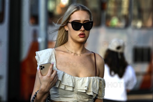 Woman wearing elegant dress wearing sunglasses strolling through a street in Tallinn, Tallinn, South Alinn, Estonia