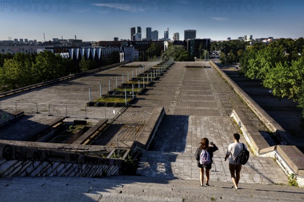 Two walkers on the abandoned platform of the city hall (Linnahall) with skyline view, Tallinn, Kelmiküla, Estonia