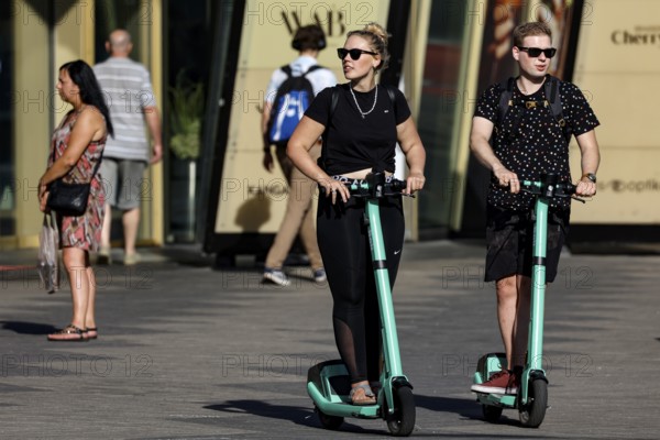 Two people ride scooters on a road in Tallinn when the sun is shining, Tallinn, South Alinn, Estonia