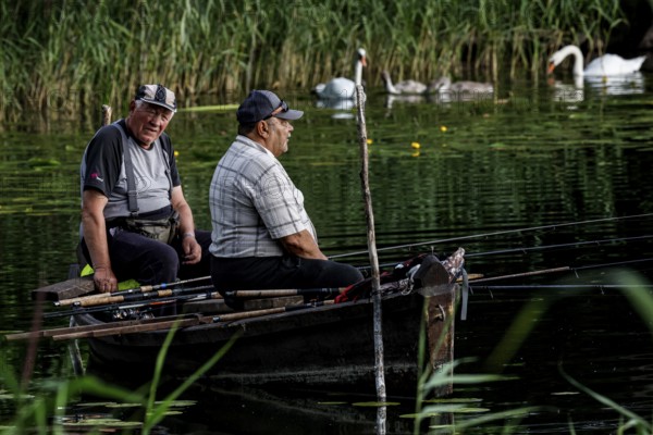 Two anglers sit in a rowboat on Lake Ilgis, surrounded by reeds and nature, Ignalina, Lithuania