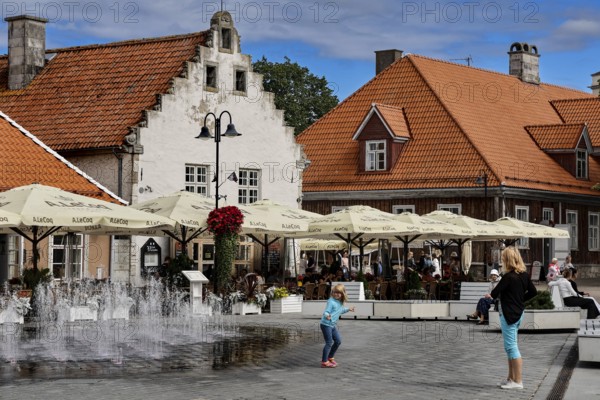 Lively scene in front of the historic Weighouse with people and fountains, Kuressaare, Saaremaa, Estonia