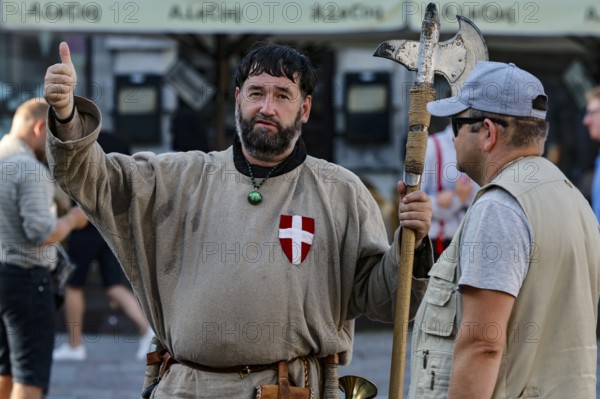 Two men, one in medieval traditional costume with an axe, on a busy square in Tallinn, Tallinn, Harju, Estonia