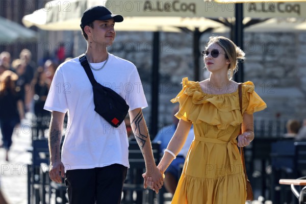 A stylish couple strolling down the clay road in the sun and holding hands, Tallinn, Harju, Estonia