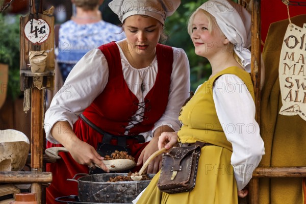 Saleswomen in traditional costumes serve customers at a medieval market, Tallinn, Harju, Estonia