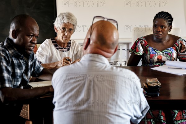 Several people in intensive discussion around a table in a closed room, Korhogo, Côte d'Ivoire