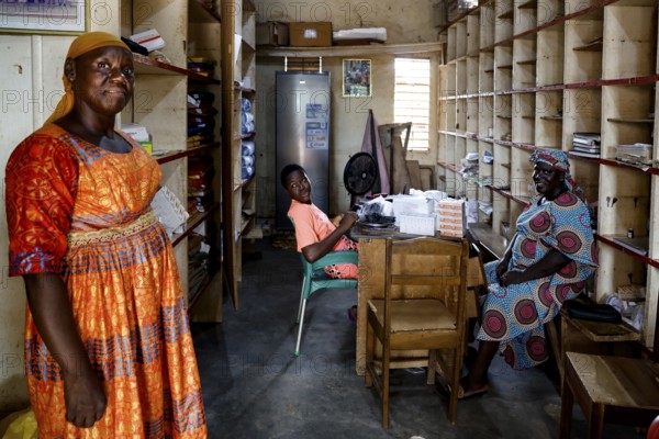 Three woman in a pharmacy scene surrounded by shelves full of medicines, bouké, region, Côte d'Ivoire