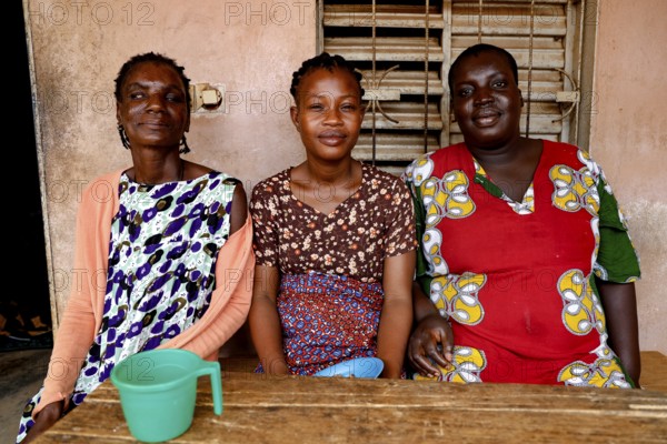 Three woman sitting together at a table smiling and enjoying company, Bouké, region, Côte d'Ivoire