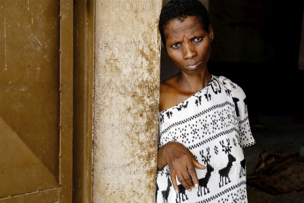 A woman wearing black and white clothes is leaning thoughtfully at a door, Bouké, region, Côte d'Ivoire