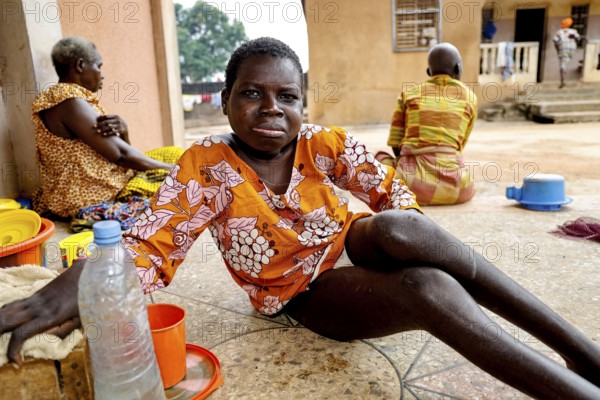 Woman sitting relaxing outdoors surrounded by water bottles, Bouké, region, Côte d'Ivoire