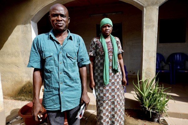 A man and a woman stand in front of their house, radiating strength together, Korhogo, CI, West Africa