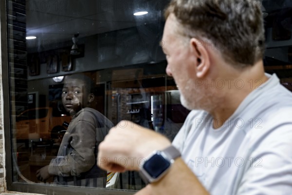 Two men in a Lebanese restaurant, one looking at the other through the window, Korhogo, CI, West Africa