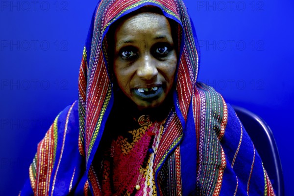 Female patient in intensive blue background and traditional clothing in hospital, Korhogo, CI, West Africa