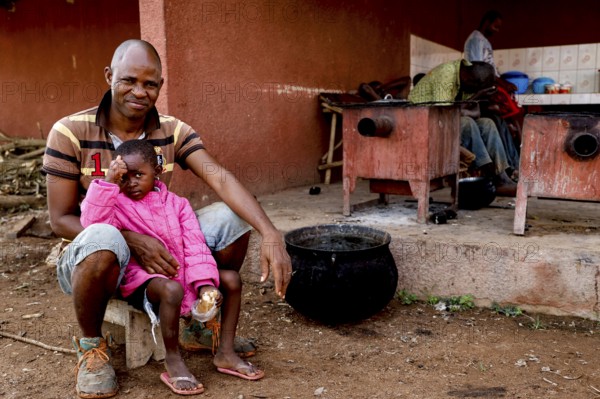 Worker sitting with his daughter in a rehabilitation center for the mentally ill, Nongotanakaha, null, Côte d'Ivoire