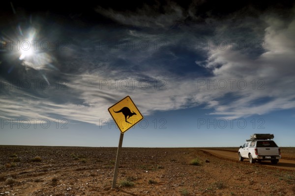 Kangaroo warning sign in an open, cloudy desert landscape near an off-road vehicle, Breakaways, South Australia, Australia
