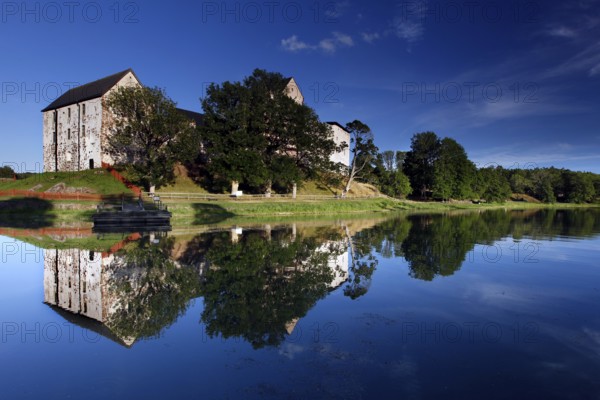Kastelholm Castle in Åland with reflection in a quiet lake and wooded shoreline landscape, zero