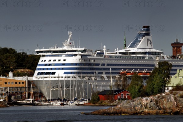 Island in Helsinki with traditional wooden house and large ferry in the background, Helsinki, Finland
