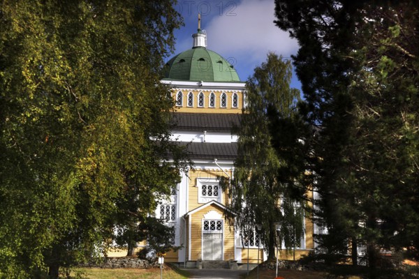 Wooden church in Kerimäki surrounded by lush greenery and blooming trees, Kerimäki, Finland