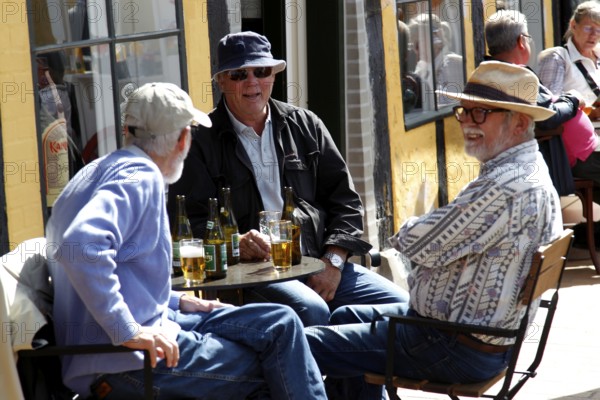 Men sitting in a street café enjoying drinks in a convivial atmosphere, Svaneke, Bornholm, Denmark
