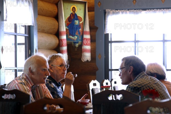 Guests sit in traditional wooden interiors in Parppeinpirtti, Ilomantsi, Parppeinvaara, Finland