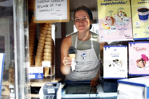 Saleswoman presents salmiac ice cream at an ice cream stand at Senaatintori, Helsinki, Senaatintori, Finland
