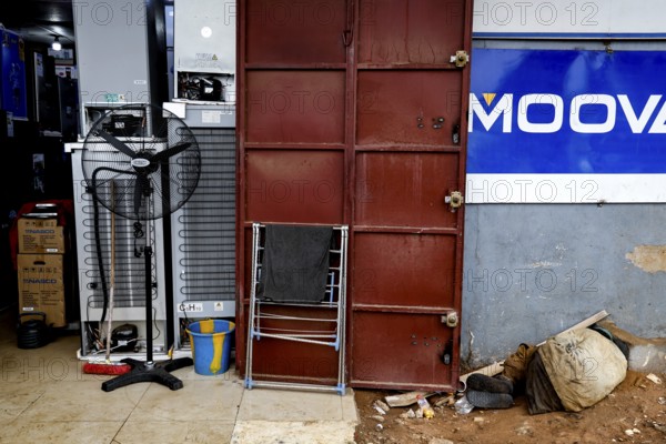 A locked door in an urban environment surrounded by dirt and scattered objects, Bouaké, Côte d'Ivoire