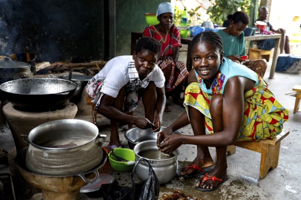 Women cooking smiling in a simple kitchen with kitchenware and pots, Bouaké, null, Côte d'Ivoire