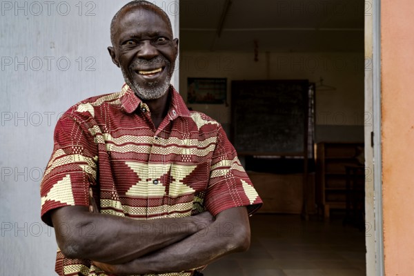 Smiling man in traditional dress standing happily at a door, Bouaké, null, Côte d'Ivoire