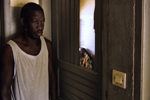 Thoughtful man standing in the shade of a door in a simple room, Bouake, null, Côte d'Ivoire