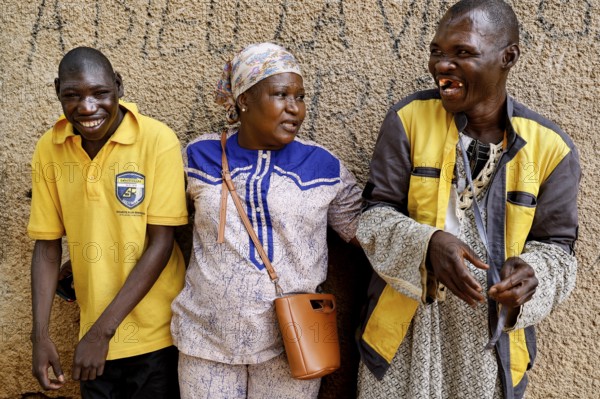 Two men interacting warmly with a nurse in front of a wall in Bouaké, Bouaké, Saint Camille, Nimbo, Côte d'Ivoire