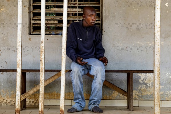 A man sits thoughtfully on a bench in a psychiatric facility in Bouaké, Bouaké, Saint Camille, Nimbo, Côte d'Ivoire