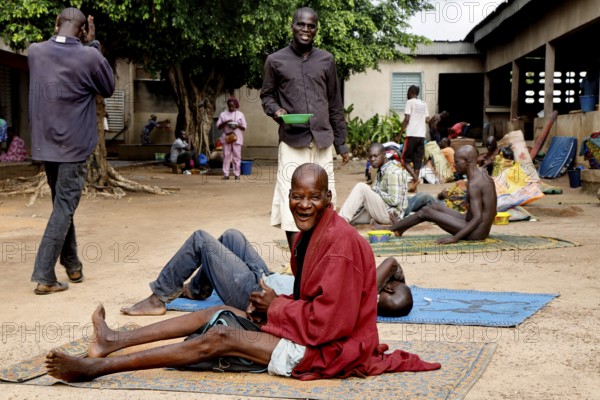 Patients sitting on mats outside in men's psychiatric ward, Bouaké, Nimbo, Côte d'Ivoire