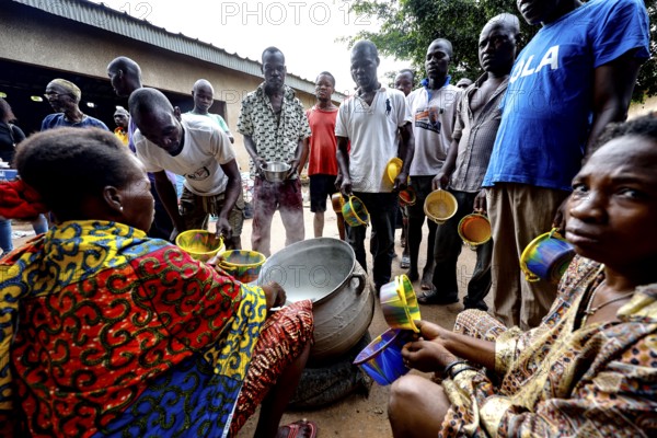Men standing and sitting serving food at Saint Camille men's psychiatry, Bouaké, Côte d'Ivoire