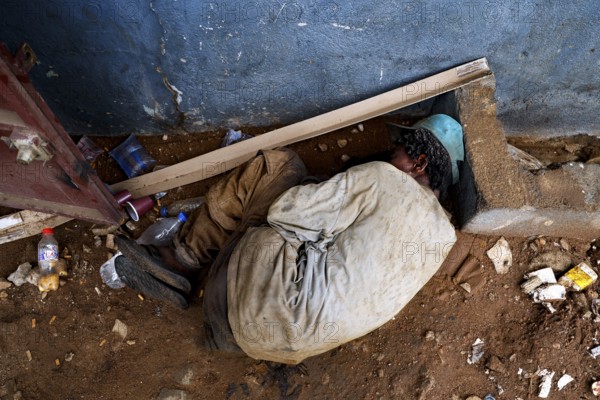 Mentally ill homeless person sleeps on the floor next to a door, Bouaké, Côte d'Ivoire